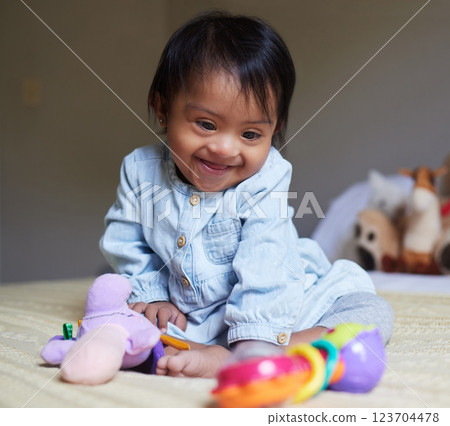 Happy, smile and baby with down syndrome playing with toys for child development in a bedroom. Happiness, learning and girl child with disability or special needs having play time on a bed at home. 123704478