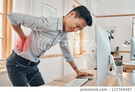 Businessman with back pain, muscle injury and burnout at office desk. Young frustrated man suffering from spinal inflammation, body discomfort or strain and healthcare stress emergency 123704487