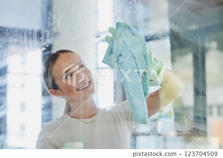 Happy, woman and cleaning window in home with cloth to wipe away water mark with proud smile. Housewife cleaner in Canada at transparent glass with detergent spray and chemical safety gloves. 123704509