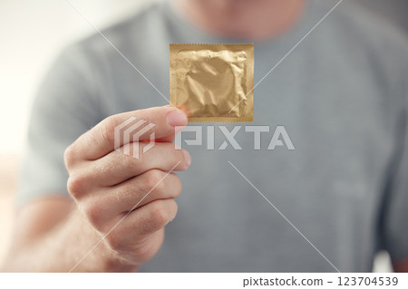 Condom in man hand for safe sex, sexual safety and hiv awareness zoom. Person with male contraceptive product for sexual risk prevention, healthcare and caution for security, trust and love choice Condom in man hand for safe sex, sexual safety and hiv awareness zoom. Person with male contraceptive product for sexual risk prevention, healthcare and caution for security, trust and love choice 123704539
