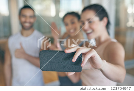 Selfie, fitness and friends with phone in hand at gym for sports, health or happy influencer with picture. Photography, group or people workout for training, thumbs up or wave closeup on social media 123704947