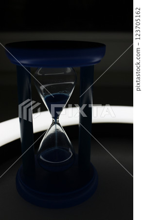 Sandglass with falling sand with soft backlight by curved lamp Sandglass with falling sand with soft backlight by curved lamp 123705162