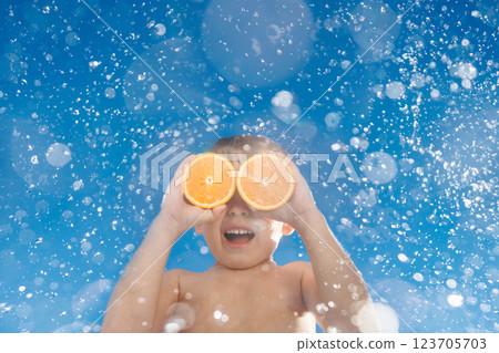 Happy child holds the orange halves like sunglasses. Kid having fun on summer vacation Happy child holds the orange halves like sunglasses. Kid having fun on summer vacation 123705703