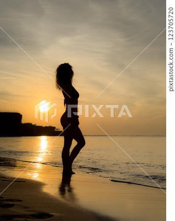 Silhouette of young woman relaxing at the beach 123705720