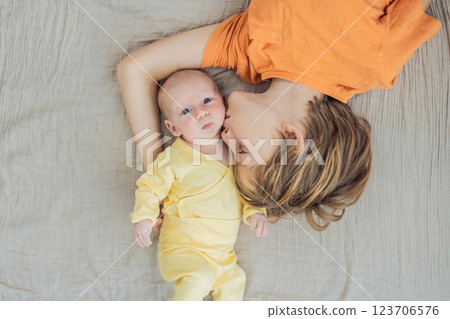 A young boy and his newborn brother lie together on a soft muslin blanket, sharing a tender sibling moment. A heartwarming scene of brotherly love, bonding, and the beginning of a lifelong connection 123706576