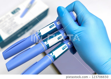 Hands in surgical gloves holding Ozempic Insulin injection pen for diabetics. 123706650