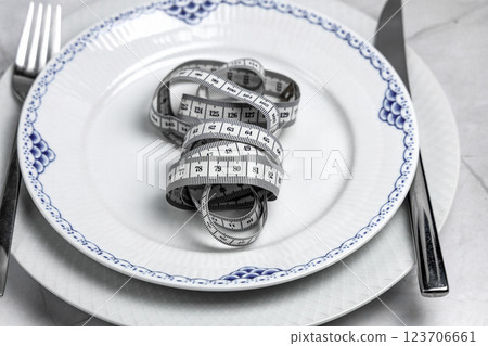 Concept of healthy eating and weight loss. Plate with measuring tape. 123706661