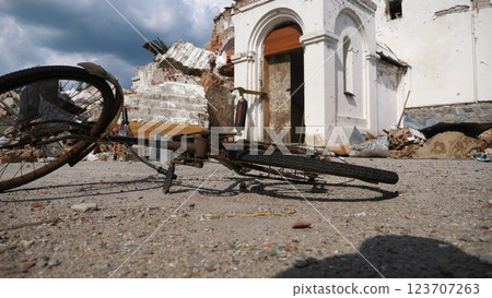 View to burned bike against the background of destroyed church at Kharkivska oblast. Ruined building after bomb attacks on ukrainian territory from russia army. russian invasion of Ukraine. Slow 123707263