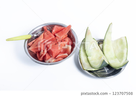 Closeup of watermelon with a spoon in bowls on a white background and watermelon rinds on a plate next to it. Closeup of watermelon with a spoon in bowls on a white background and watermelon rinds on a plate next to it. 123707508