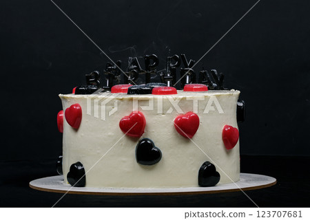 Birthday cake decorated with black candles shaped Happy Birthday inscription, hearts shaped jellies. Birthday cake decorated with black candles shaped Happy Birthday inscription, hearts shaped jellies. 123707681