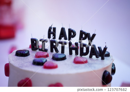 Birthday cake decorated with black candles shaped Happy Birthday inscription, hearts shaped jellies. 123707682