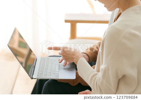 The hands of a couple sitting on a sofa and looking at a computer 123709884