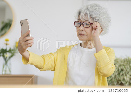 戴眼鏡的老年婦女看著智慧型手機螢幕 123710065