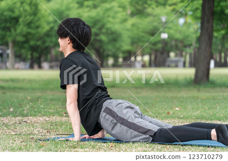 一個年輕人在公園的瑜珈墊上做瑜珈/皮拉提斯（眼鏡蛇式） 123710279