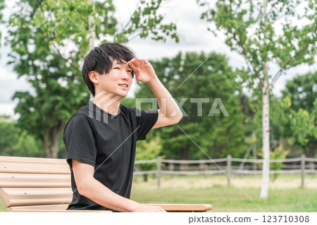 Asian man resting on a park bench during exercise (muscle fatigue, muscle pain, overtraining syndrome) Asian man resting on a park bench during exercise (muscle fatigue, muscle pain, overtraining syndrome) 123710308