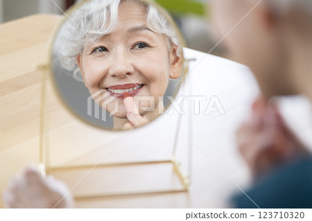 一位老年婦女在鏡子前化妝 123710320