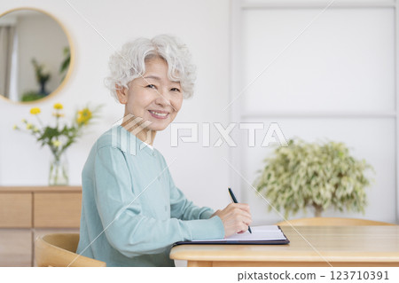 Smiling senior woman holding a pen, looking at the camera 123710391