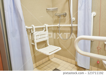 A shower room with a plastic chair in a hospital, designed for the disabled and people with limited mobility, with tiled floors and walls. High quality photo A shower room with a plastic chair in a hospital, designed for the disabled and people with limited mobility, with tiled floors and walls. High quality photo 123711192