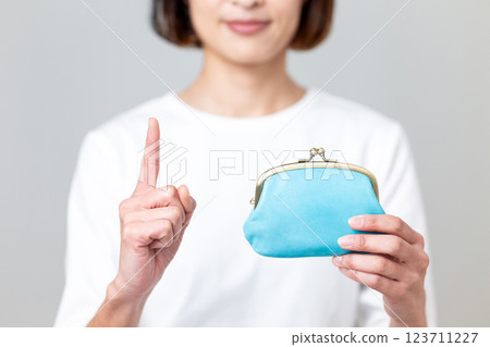 A middle-aged woman holding a blue purse and pointing her index finger up 123711227