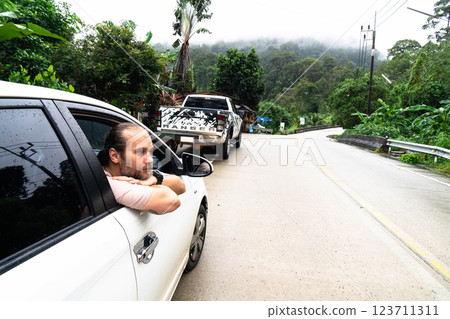 Exploring the winding roads of Koh Phangan surrounded by vibrant green nature and hills. 123711311