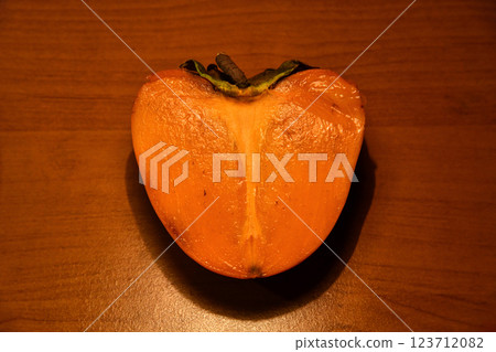 A ripe persimmon on a plate on a wooden background, close-up. Persimmon A ripe persimmon on a plate on a wooden background, close-up. Persimmon 123712082