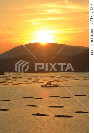 A ferry slowly sailing through the Seto Inland Sea at dusk 123712189