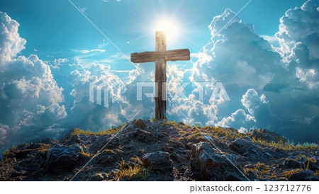 Illuminated wooden cross on grassy hilltop under bright blue sky with clouds. Symbol of faith, spirituality, and hope. 123712776