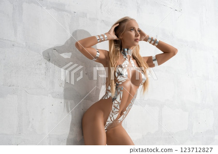 Model poses in reflective fashion against a textured wall in bright lighting Model poses in reflective fashion against a textured wall in bright lighting 123712827