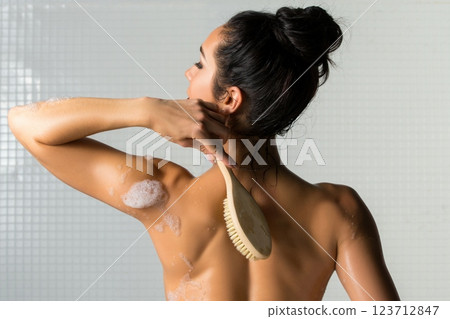 Woman applying body scrub while taking a shower in a modern bathroom 123712847