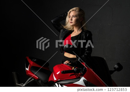 Confident woman poses with sports motorcycle in stylish urban setting Confident woman poses with sports motorcycle in stylish urban setting 123712853