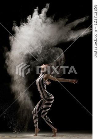 Dancer in striped outfit creating artistic cloud of powder at performance 123712859