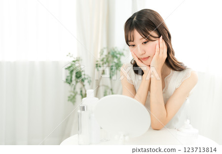 Young Asian woman worried about skin problems while looking in the mirror (skin care) Young Asian woman worried about skin problems while looking in the mirror (skin care) 123713814