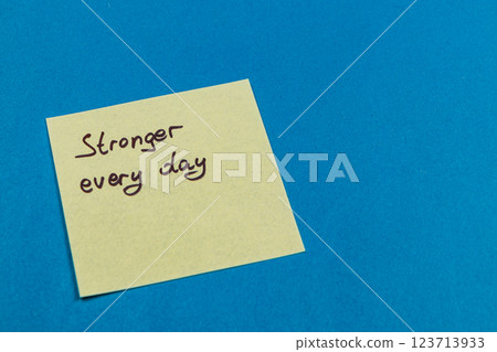 Encouraging note on yellow sticky paper against a blue background 123713933