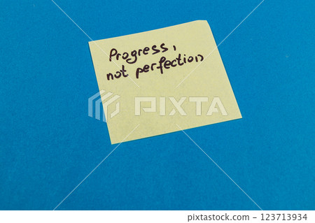 Encouragement note on sticky pad emphasizing progress over perfection Encouragement note on sticky pad emphasizing progress over perfection 123713934