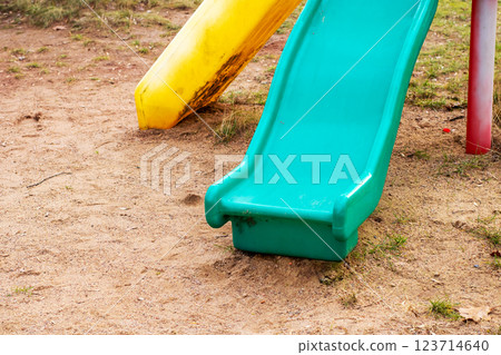 A blue slide in sandy area, shaded by a tree in the background 123714640