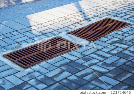 Two drains are positioned closely on a brick sidewalk Two drains are positioned closely on a brick sidewalk 123714646