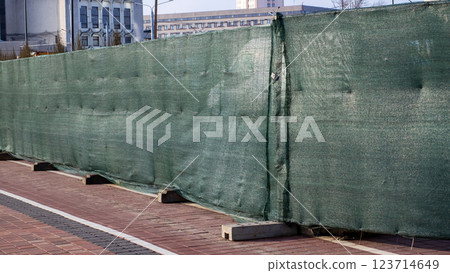 There is a green fence surrounding a bike lane located in a parking lot There is a green fence surrounding a bike lane located in a parking lot 123714649