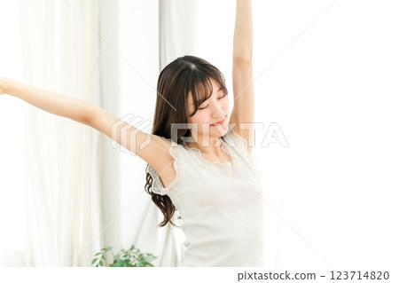 A woman basking in the morning sun in front of the curtains when she wakes up (deep breathing) 123714820