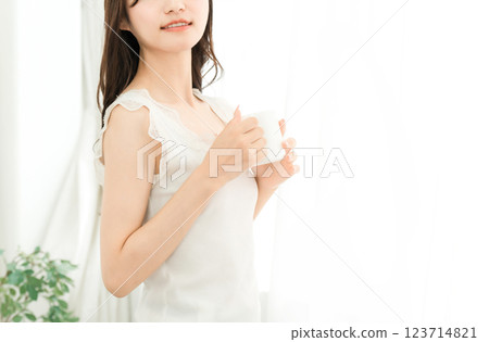 Smiling Asian woman drinking hot water, coffee, hot drink, cafe au lait, cafe latte at home in the morning Smiling Asian woman drinking hot water, coffee, hot drink, cafe au lait, cafe latte at home in the morning 123714821