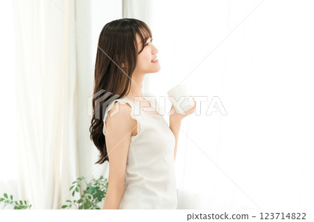 Smiling Asian woman drinking hot water, coffee, hot drink, cafe au lait, cafe latte at home in the morning Smiling Asian woman drinking hot water, coffee, hot drink, cafe au lait, cafe latte at home in the morning 123714822
