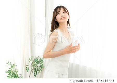 Smiling Asian woman drinking hot water, coffee, hot drink, cafe au lait, cafe latte at home in the morning Smiling Asian woman drinking hot water, coffee, hot drink, cafe au lait, cafe latte at home in the morning 123714823