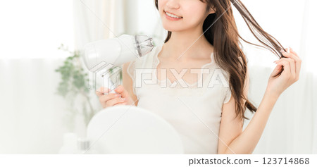 A woman blow-drying her hair with a hair dryer (hair care) A woman blow-drying her hair with a hair dryer (hair care) 123714868