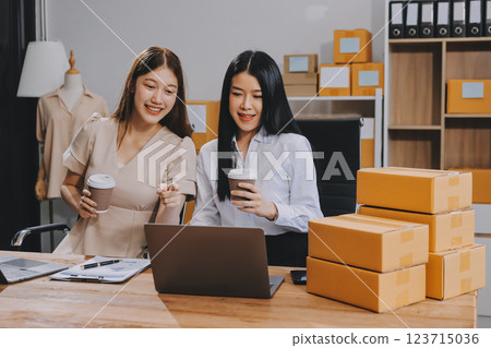 Startup SME small business entrepreneur of freelance Asian woman using a laptop with box Cheerful success Asian woman her hand lifts up online marketing packaging box and delivery SME idea concept Startup SME small business entrepreneur of freelance Asian woman using a laptop with box Cheerful success Asian woman her hand lifts up online marketing packaging box and delivery SME idea concept 123715036
