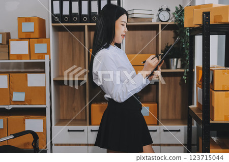 Startup SME small business entrepreneur of freelance Asian woman using a laptop with box Cheerful success Asian woman her hand lifts up online marketing packaging box and delivery SME idea concept 123715044