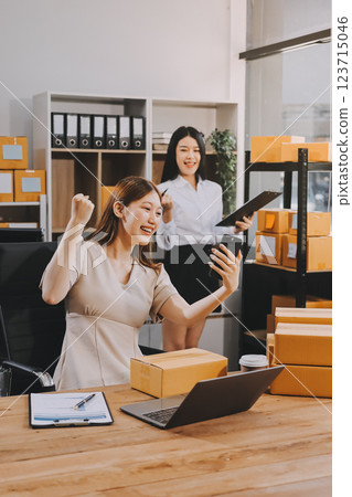 Startup SME small business entrepreneur of freelance Asian woman using a laptop with box Cheerful success Asian woman her hand lifts up online marketing packaging box and delivery SME idea concept 123715046