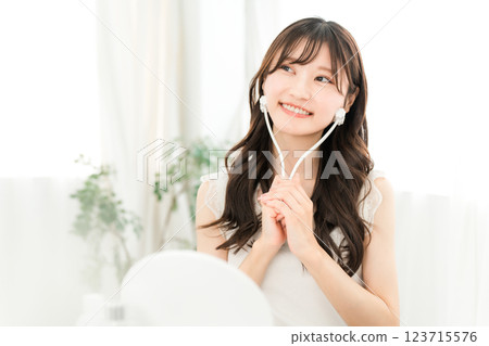 Asian woman massaging with facial roller Asian woman massaging with facial roller 123715576