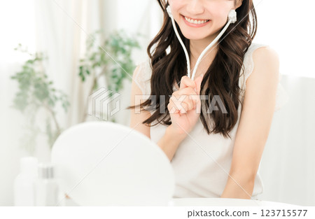 Asian woman massaging with facial roller Asian woman massaging with facial roller 123715577
