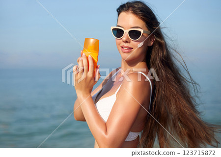 Applying Sunscreen at the Beach on a Sunny Summer Day to Protect Skin From Harmful UV Rays 123715872