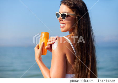 Enjoying Summer at the Beach While Applying Sunscreen for Skin Protection and Care Enjoying Summer at the Beach While Applying Sunscreen for Skin Protection and Care 123715886