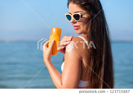 Enjoying Summer at the Beach While Applying Sunscreen for Sun Protection and Skincare Enjoying Summer at the Beach While Applying Sunscreen for Sun Protection and Skincare 123715887